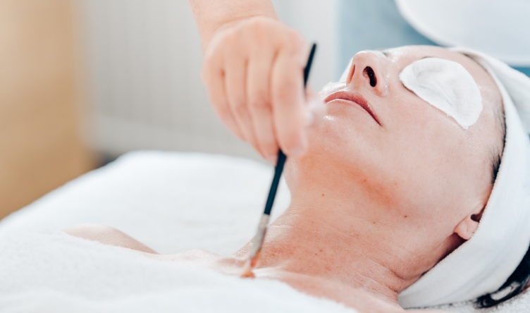 Dame bei einer Sch&ouml;nheitsbehandlung gegen Couperose mit aufgetragenem Pflegeprodukt auf Gesicht und Dekollet&eacute; 